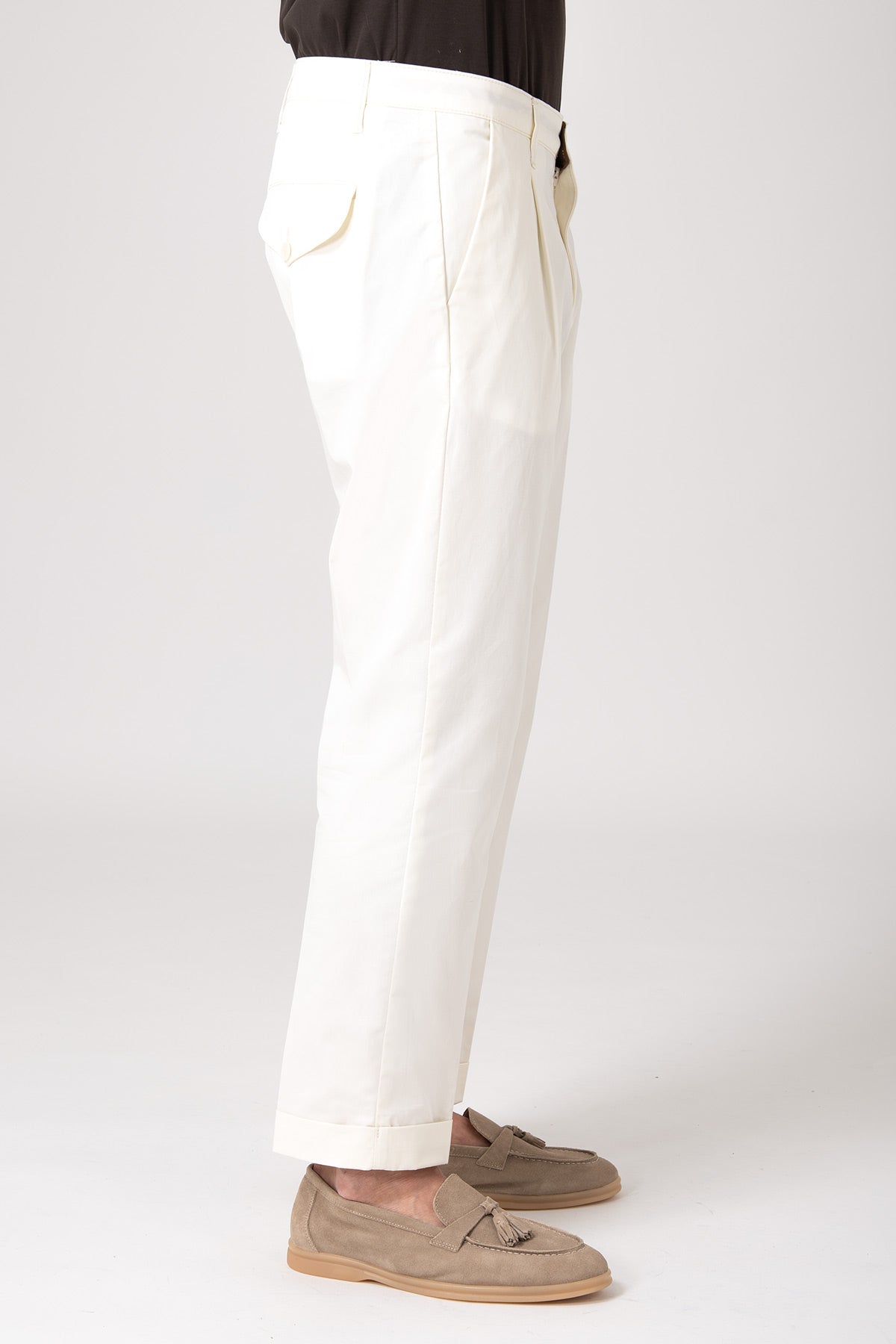 Man wearing beige high-waisted pleated pants side view