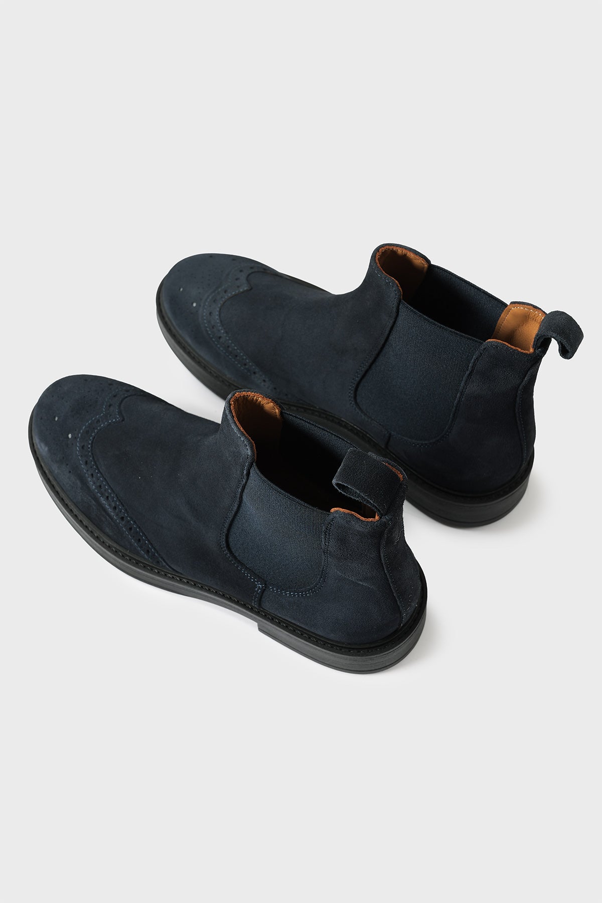 Blue suede Chelsea boots with elastic side panels and brogue detailing, high three-quarter view