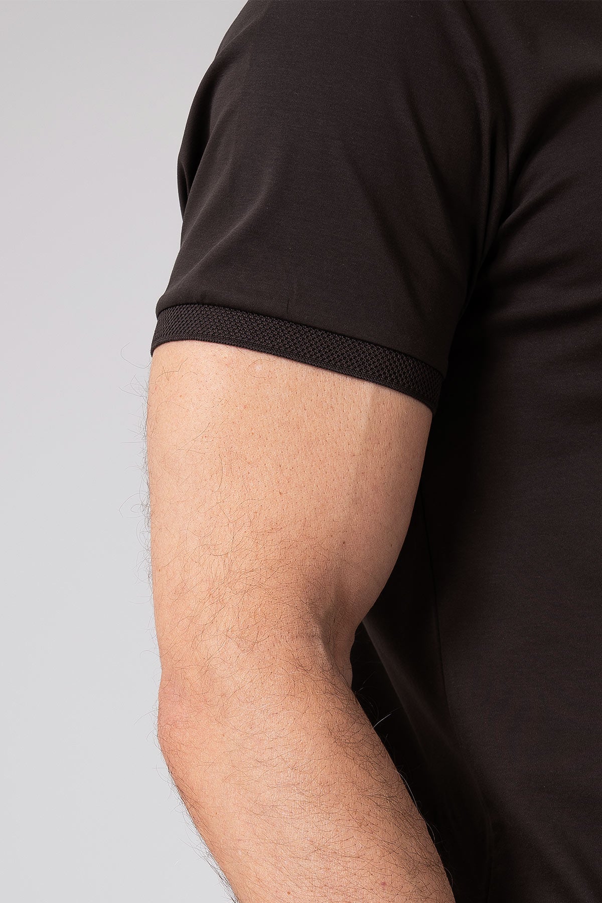 Close-up side view of a man wearing black mercerized cotton T-shirt showing short sleeve detail